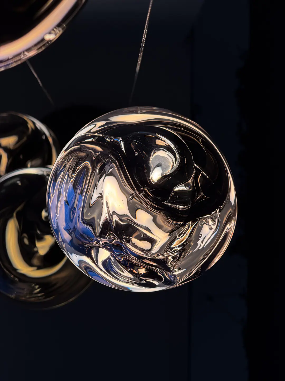 Mirrored glass pendant lights hanging in the dark, warping the room in their reflections
